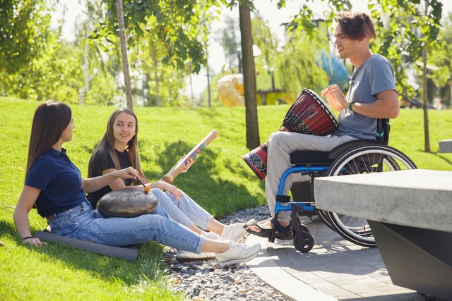 Happy-handicapped-man-wheelchair-spending-time-with-friends-playing-live-instrumental-music-outdoors_original